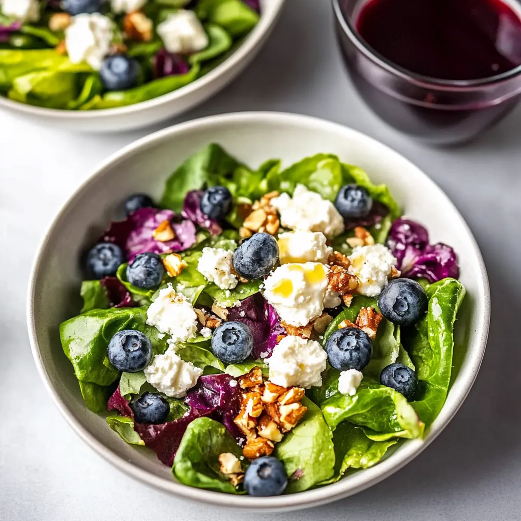A bowl of salad with blueberries and feta cheese.