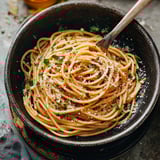 Spaghetti tangled up with melty cheese and chopped herbs.