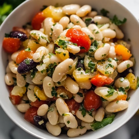 A bowl of food with tomatoes, beans, and herbs.